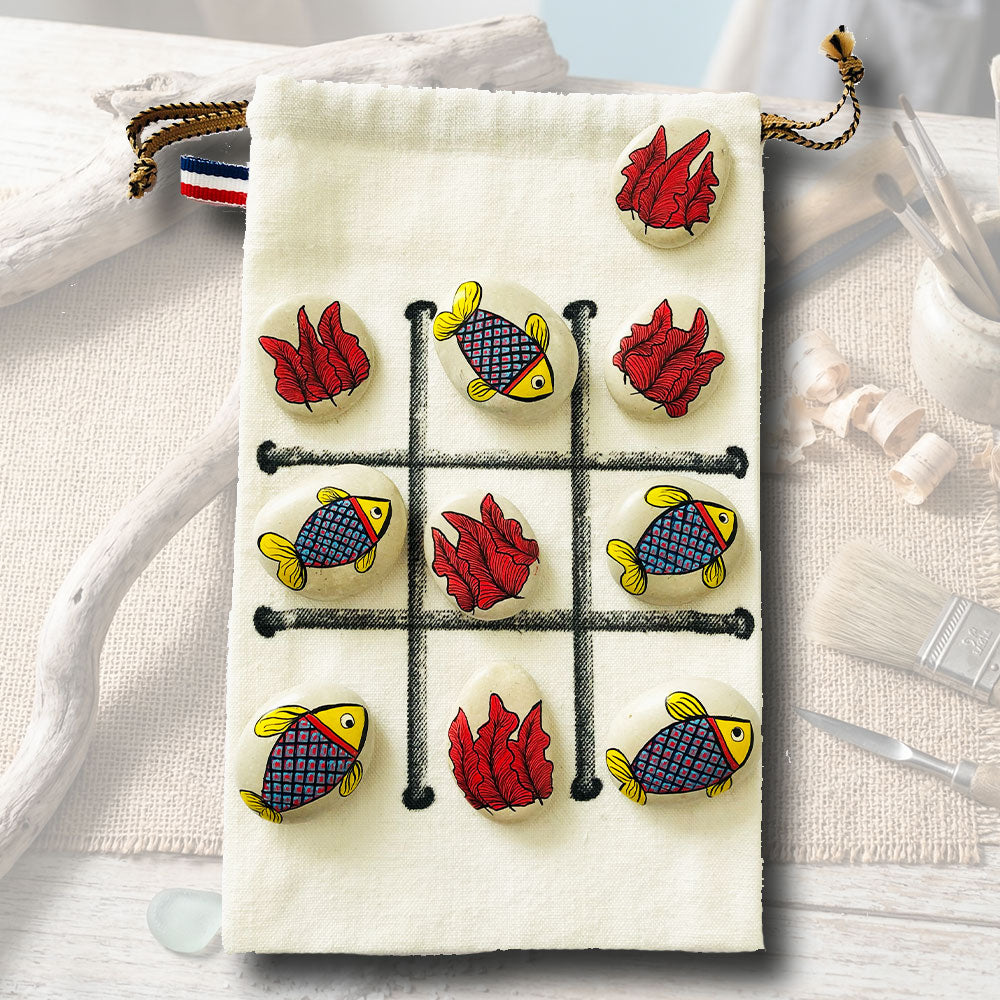 Jeu de morpion sur galets peints, motifs poissons multicolores et algues rouges, sachet en toile beige avec tracé de jeu noir, artisanat L'Atelier du Ressac.