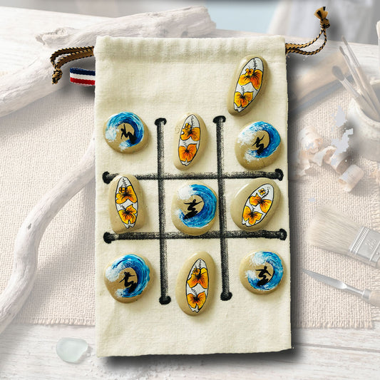 Jeu de morpion artisanal, galets peints avec motifs surfeurs et fleurs d'hibiscus jaunes, sachet en toile beige 15x21cm, L'Atelier du Ressac.