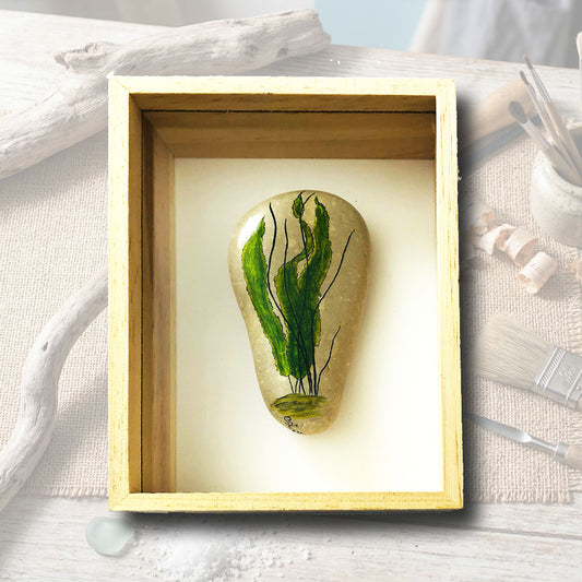 Galet naturel clair peint à la main avec un motif minimaliste d'algues vertes et lignes noires, cadre coffret bois clair 15x21cm, artisanat d'art Auvergne L'Atelier du Ressac.